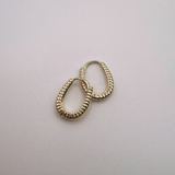 Gold huggie hoop earrings on a light gray background