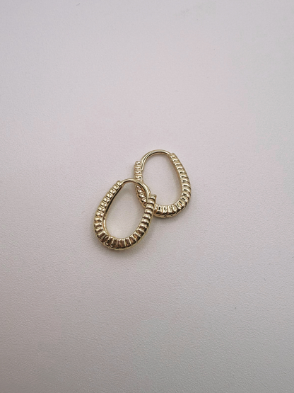 Gold huggie hoop earrings on a light gray background