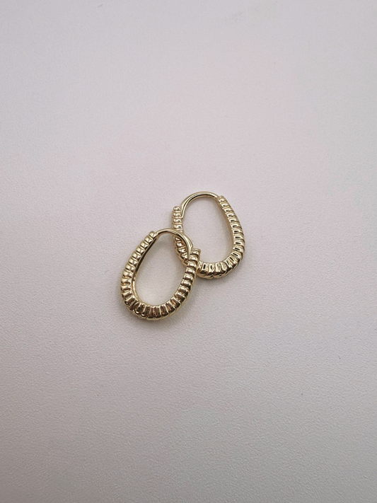 Gold huggie hoop earrings on a light gray background