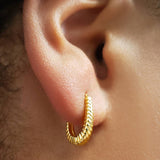 Close-up of an ear wearing a gold huggie hoop earring